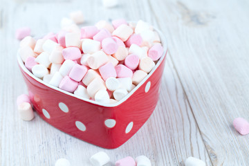 marshmallows in heart shape bowl on a wooden table