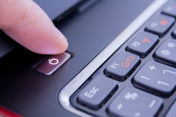 a finger is pushing the power button to wake laptop up