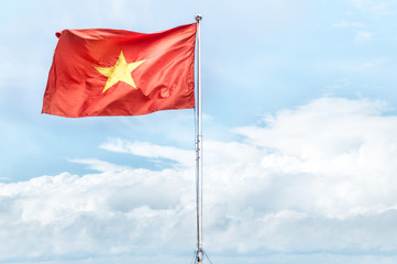 Red national flag of Vietnam waving in blue sky.