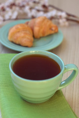 Cup of tea and croissants near blossoming branches
