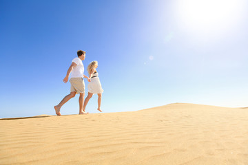 Couple running having fun holding hands under sun