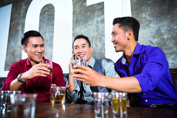 Asian friends drinking shots in nightclub