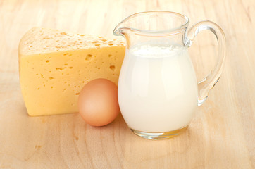 Big piece of cheese, glass jug with milk