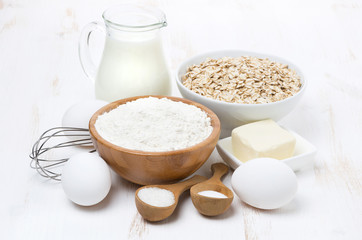 milk, cereal and ingredients for baking on white wooden table