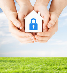 hands holding paper house with lock