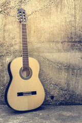 Acoustic guitar against a grunge textured wall.