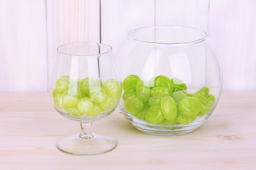 Color candies in glasses on wooden background