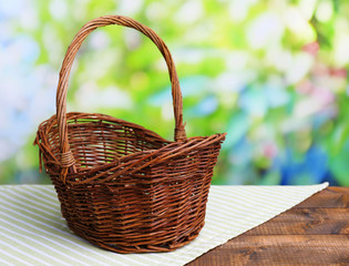 Fototapeta na wymiar Empty wicker basket on wooden table, on bright background