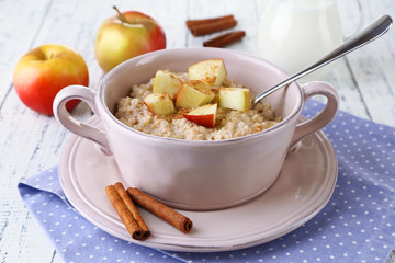 Tasty oatmeal with apples and cinnamon on wooden table