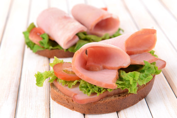Delicious sandwiches with lettuce and ham on table close-up