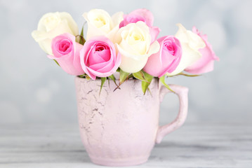 Beautiful roses in cup on light background