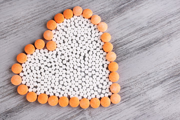 Heart of pills on wooden background