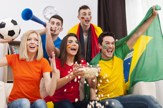 Group of multinational people cheering football match at home