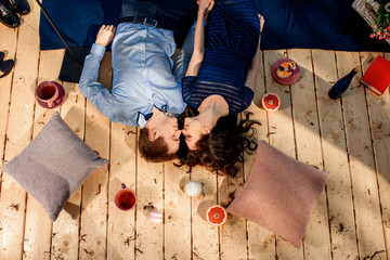 couple lying on wood floor with pillows and sweets