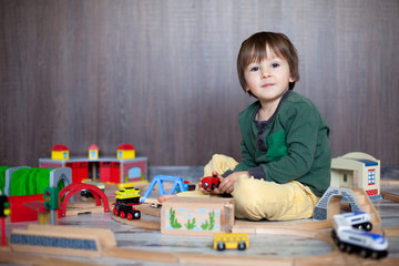Little toddler boy playing with wooden railway, indoors.