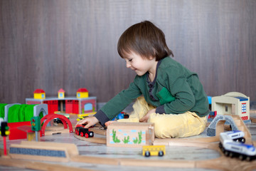 Little toddler boy playing with wooden railway, indoors.