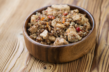 Stewed buckwheat with chicken fillet in a wooden bowl, close-up