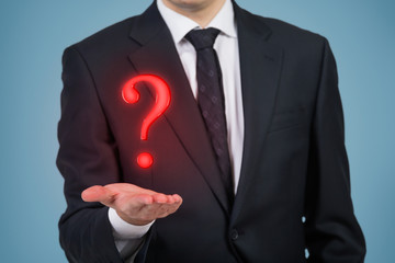 Businessman holding a red question mark, blue background