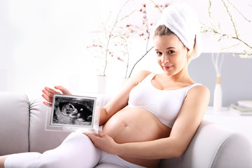 Kobieta w ciąży pokazuje usg dziecka - obrazy, fototapety, plakaty