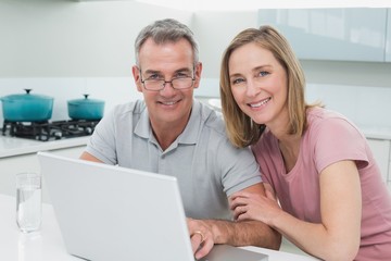 Portrait of a couple using laptop in kitchen