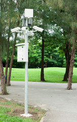 Security surveillance camera near green forest