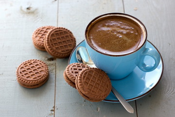 A cup of black coffee and chocolate biscuits
