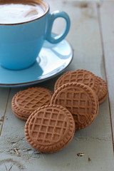 A cup of black coffee and chocolate biscuits