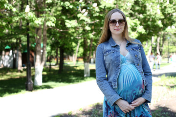 Young pregnant woman in summer park