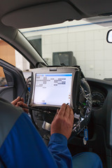 Car service worker inside car programming service computer.