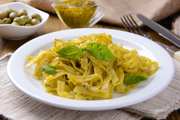 Delicious pasta with pesto on plate on table close-up