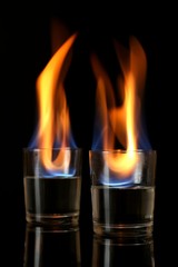 Glasses with burning alcohol on black background