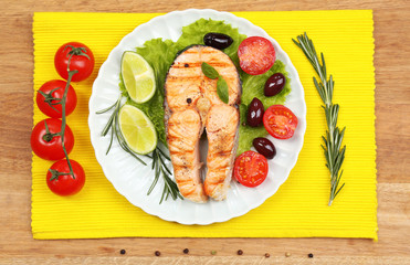 Tasty grilled salmon with vegetables, on wooden table