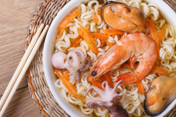 Asian soup with seafood and noodles with chopsticks close up.
