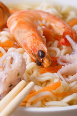 soup with shrimps, octopuses and noodles and chopsticks vertical