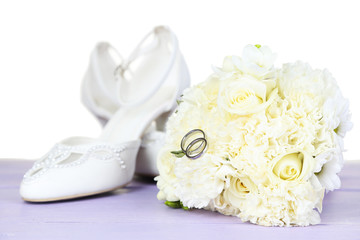 Beautiful wedding bouquet and shoes on table on light
