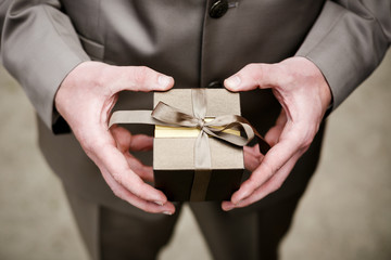 Groom in brown suit holding box (case) with wedding rings