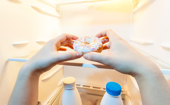 photo of female hand taking donut from refrigerator
