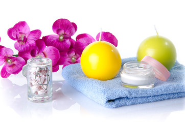 Moisturizing cream with candles and flower on a towel