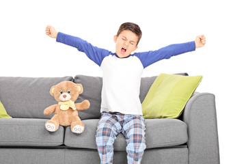 Little boy yawning seated on couch