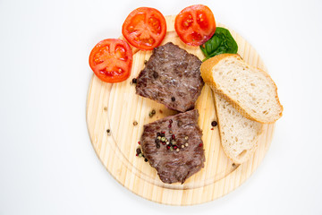 Steak auf einem Holzteller mit Tomaten und Weißbrot