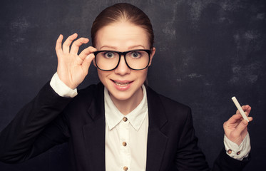 business woman teacher with glasses and a suit with chalk   at a
