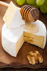 camembert cheese with grapes, honey and nuts on wooden backgroun
