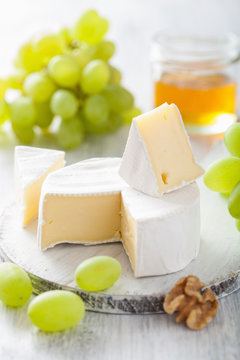 camembert cheese with grapes, honey and nuts on wooden backgroun
