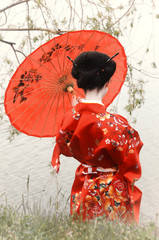 Geisha with red umbrella at the riverside (back view) © rodjulian
