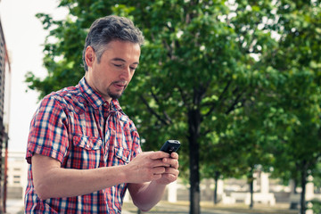 Man in short sleeve shirt texting on phone