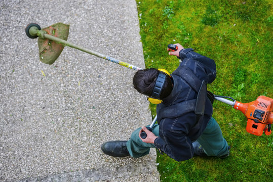 gardener using corded string trimmer in a park
