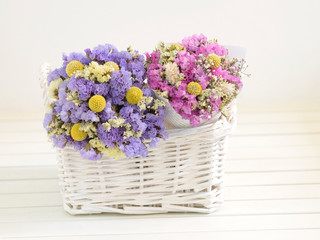 Two small bouquets of dried flowers put into a white basket.
