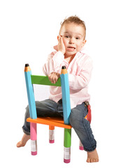 kleiner junge sitzt verkehrt herum auf einem stuhl