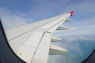 Airplane wing in the blue sky with white clouds