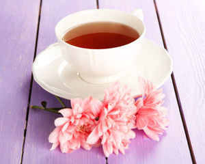 Fototapeta na wymiar Pink chrysanthemums and cup of tea on wooden table
